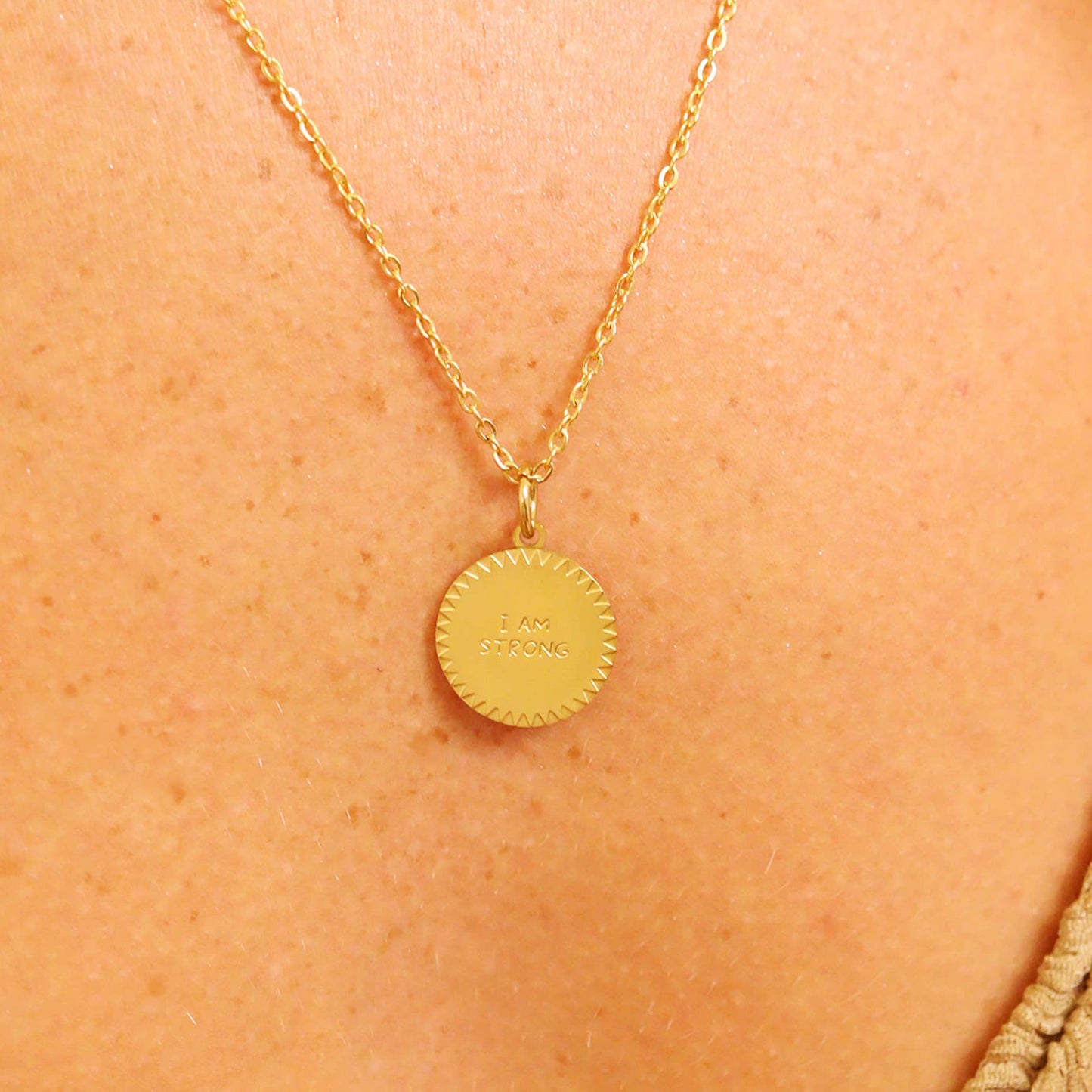 Gold necklace with a round pendant on a person's neck