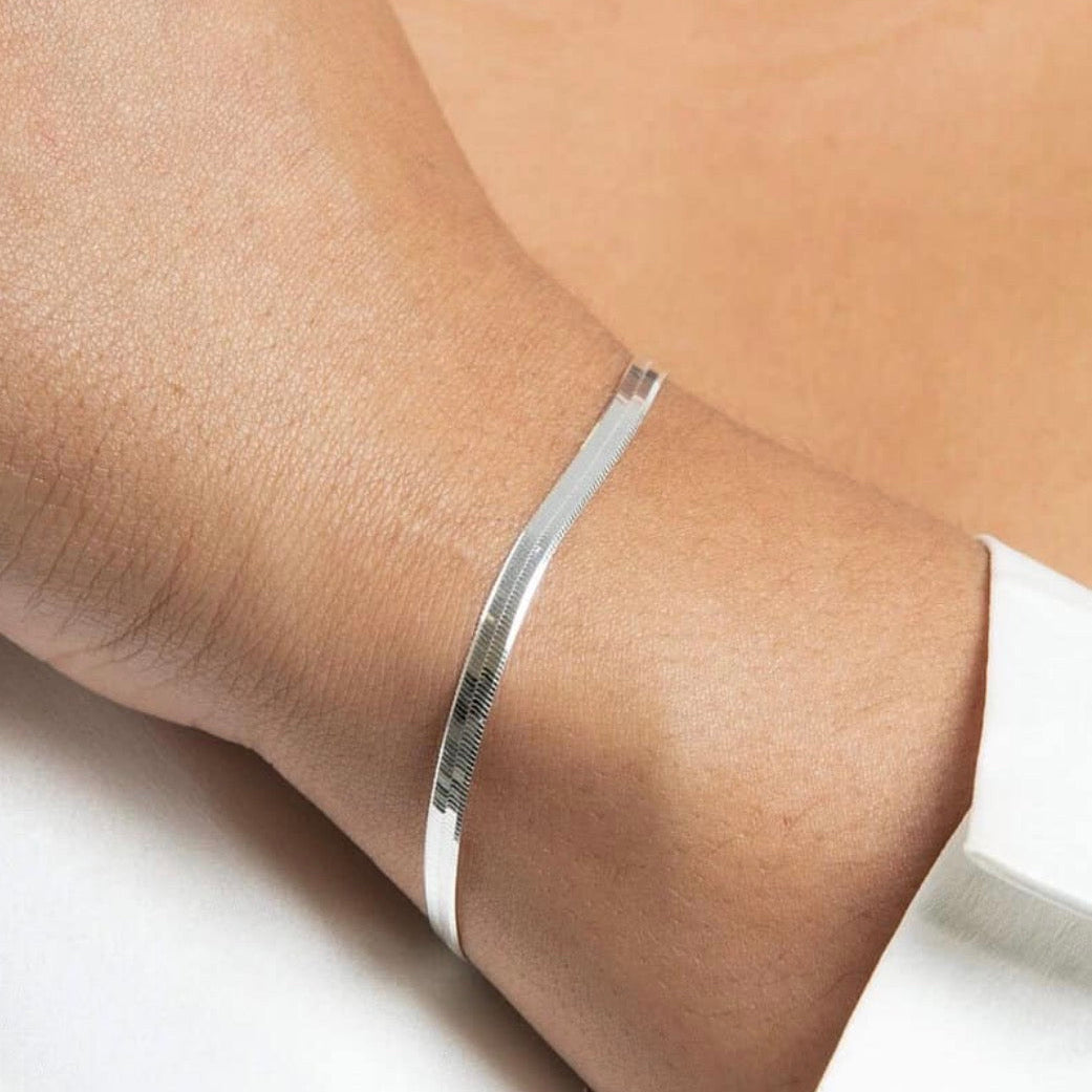 Silver bracelet on a person's wrist with a neutral background