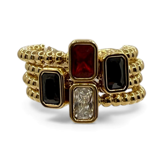 Gold ring with red, black, and clear gemstones on a white background