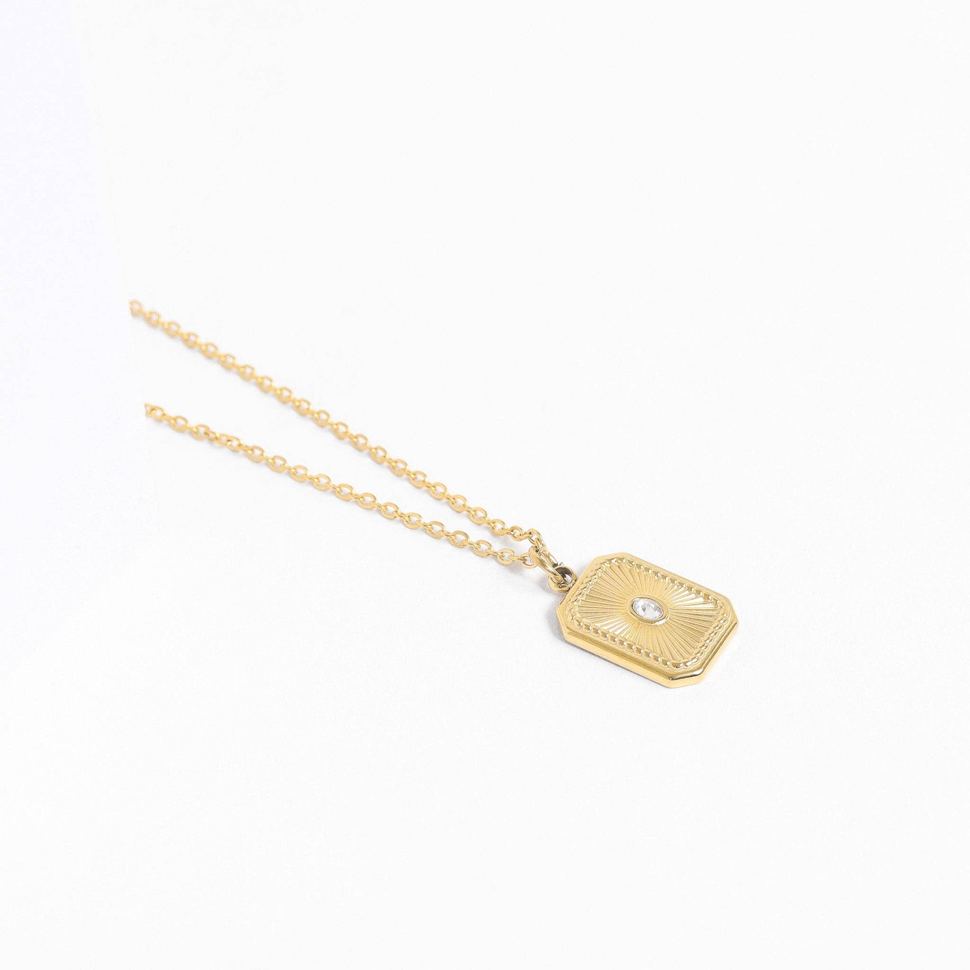 Gold necklace with a hexagonal pendant on a white background
