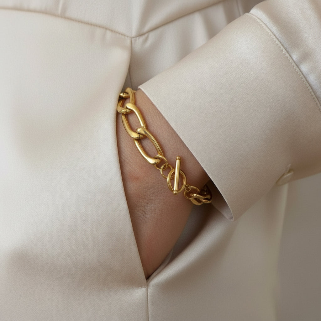 Gold chain bracelet on a wrist with a neutral background