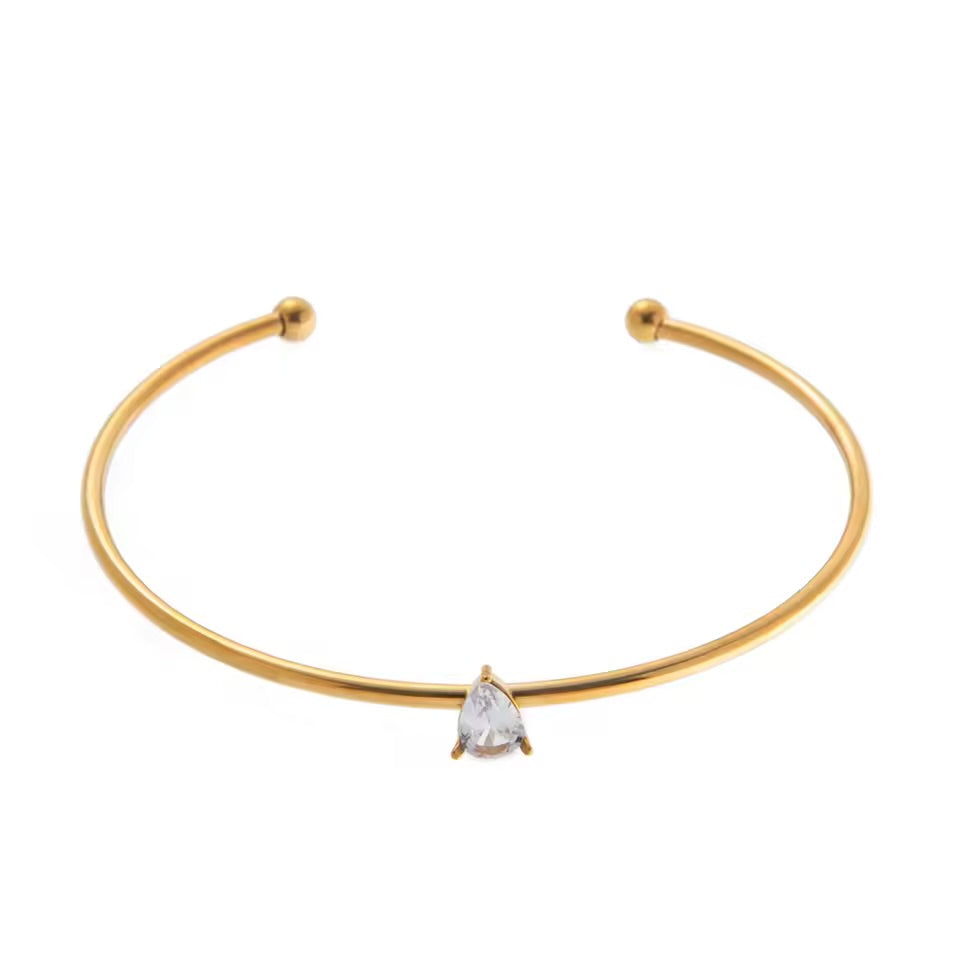 Gold bracelet with a clear gemstone on a white background
