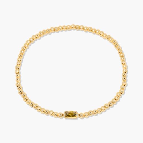 Gold bracelet with a central green gemstone on a white background