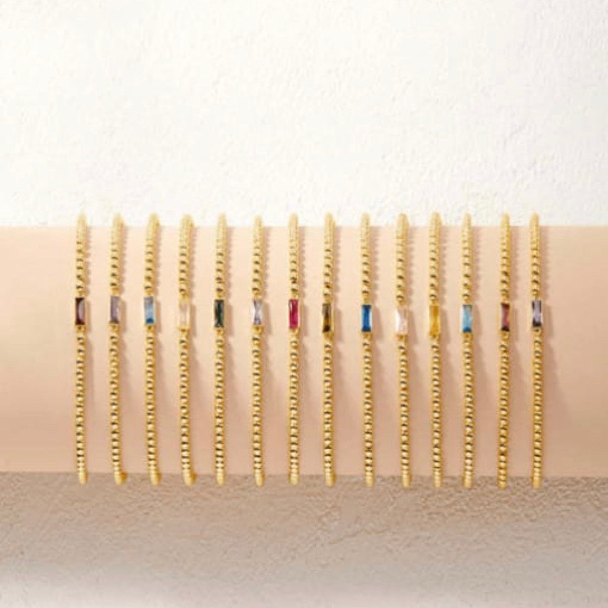 Gold chain earrings on a beige display with a white background