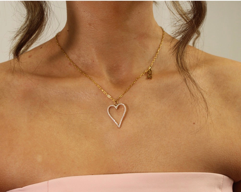 Gold necklace with a heart-shaped pendant on a person's neck