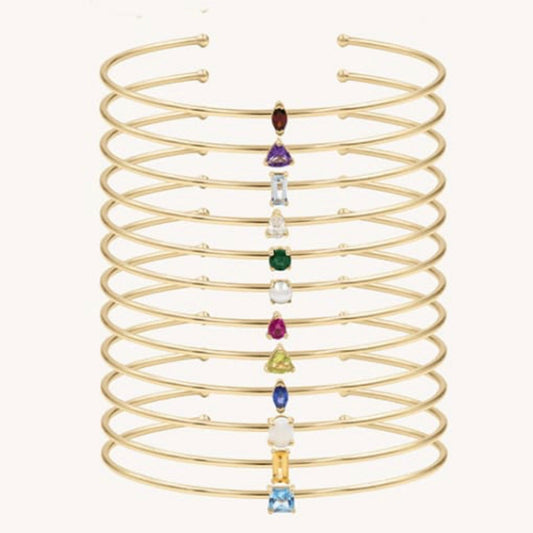 Gold spiral bracelet with colorful gemstones on a white background
