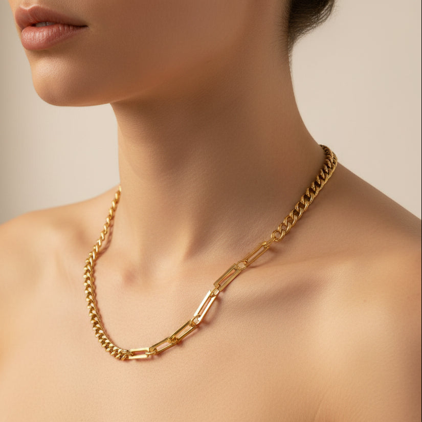 Gold chain necklace worn by a person against a neutral background