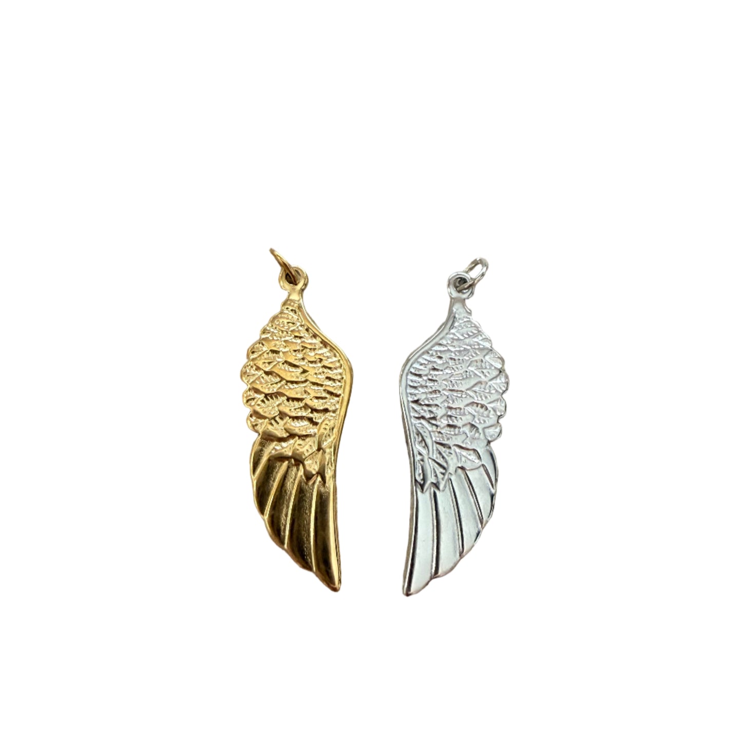 Gold and silver wing-shaped charms on a wooden surface