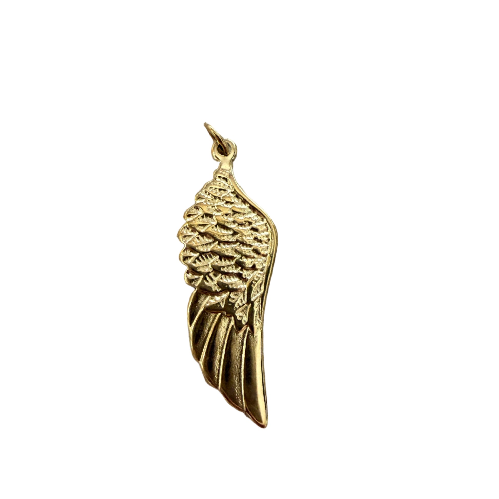 Gold wing-shaped pendant on a wooden surface