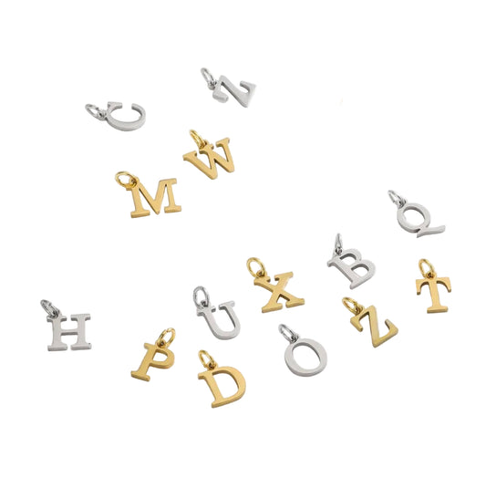 Gold and silver letter pendants on a white surface with dried flowers.