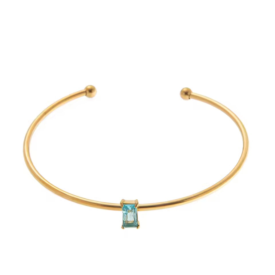 Gold bracelet with a blue gemstone on a white background
