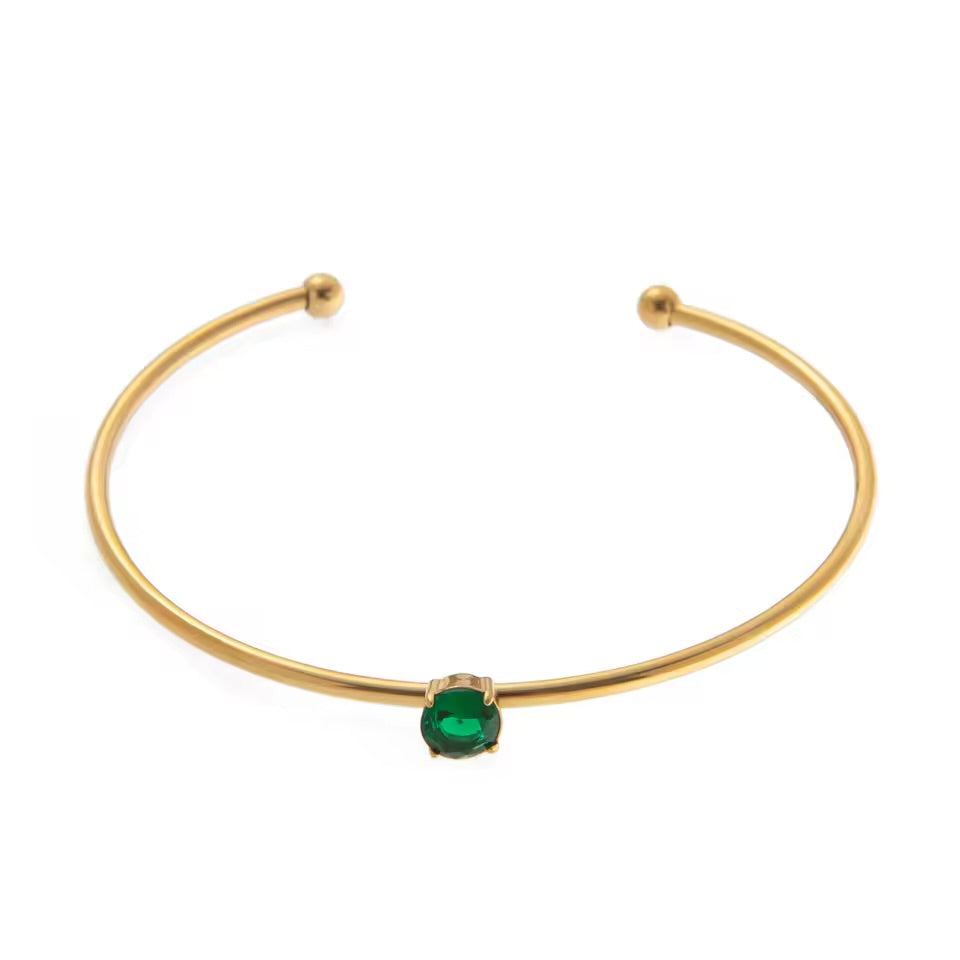 Gold bracelet with a green gemstone on a white background