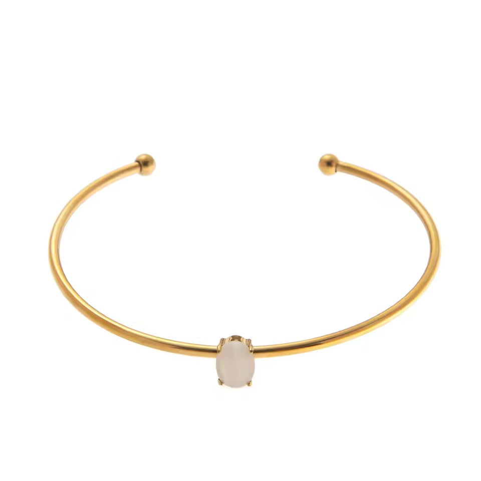 Gold bracelet with a central gemstone on a white background