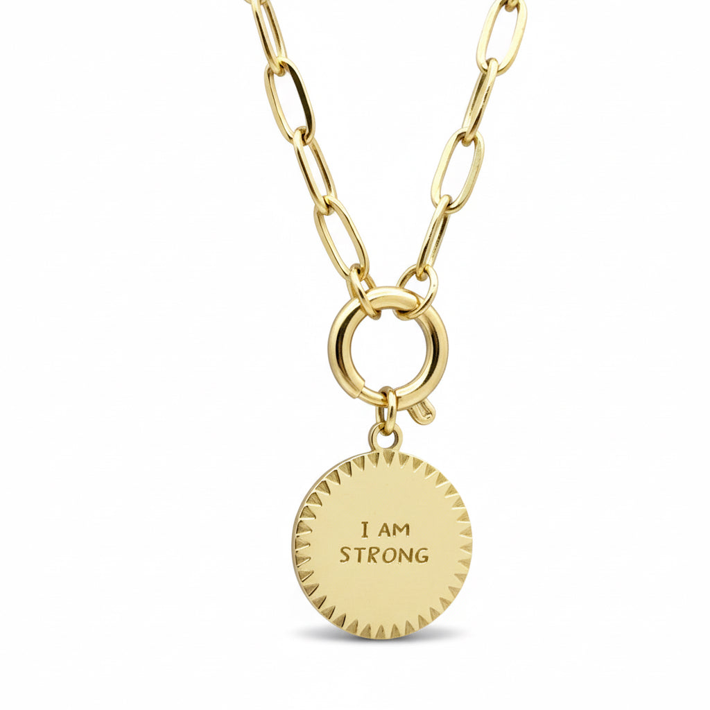Gold necklace with a black pendant that says 'I AM STRONG' on a white background