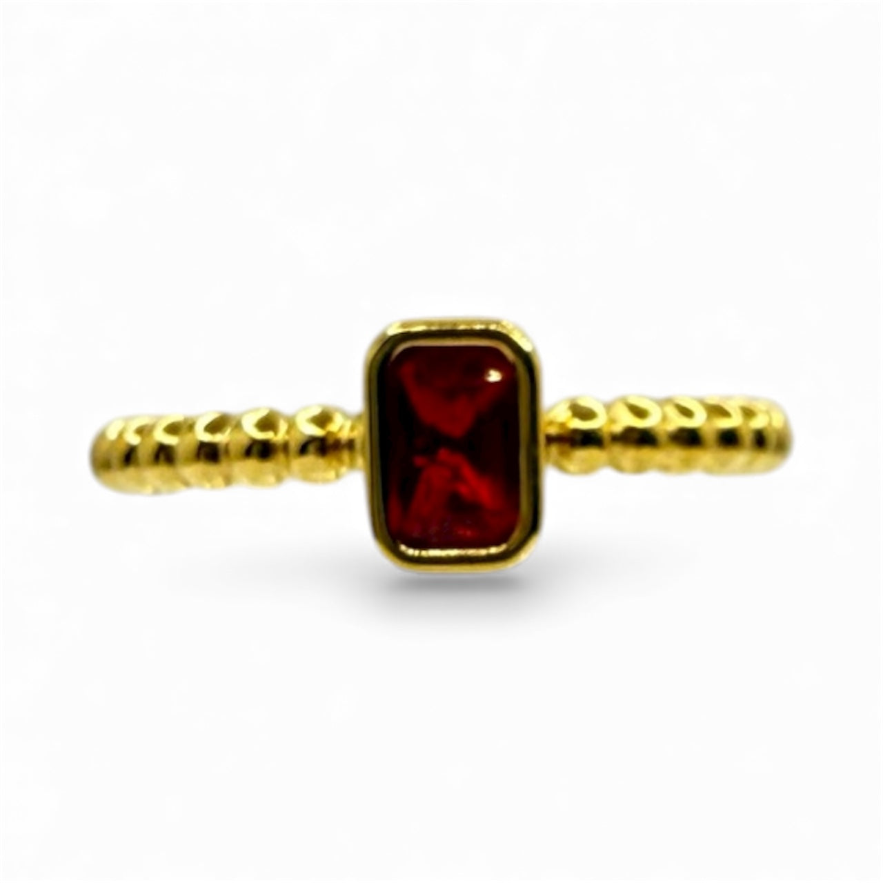 Gold ring with a red gemstone on a white background